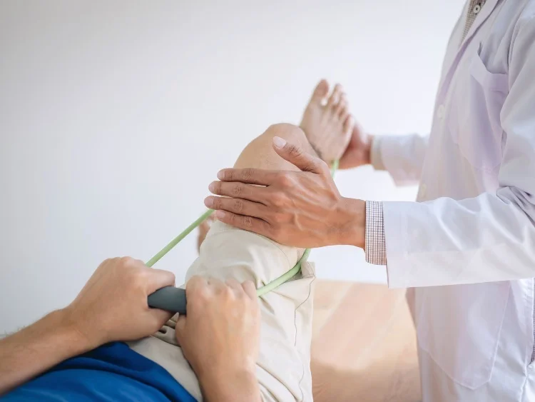 patient pulling on elastic band while doctor helps with physical therapy