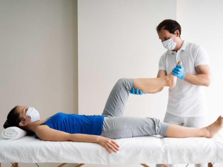 woman bending her knee with help from a physical therapist