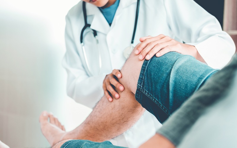 man in jean shorts getting knee checked by doctor