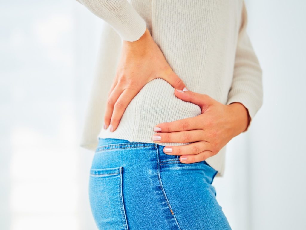 Side image of woman clutching hip