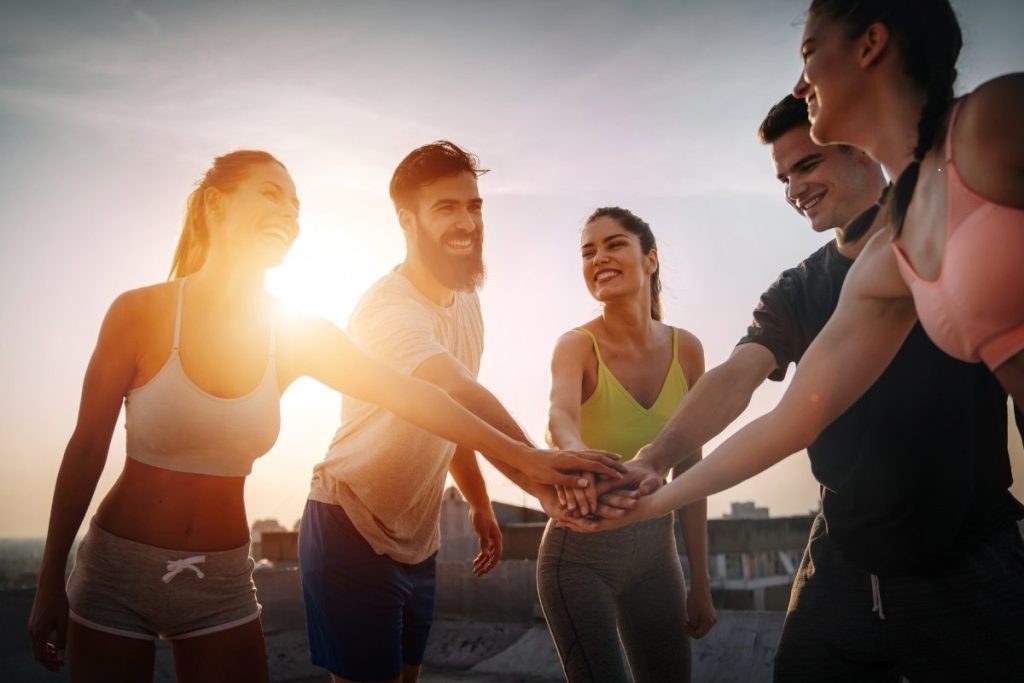 Group of friends in a huddle with the sun setting in the background