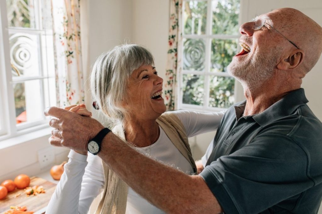 Male and female having a laugh and dancing at home