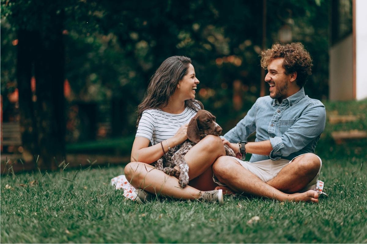 Male and female sat on grass with their dog