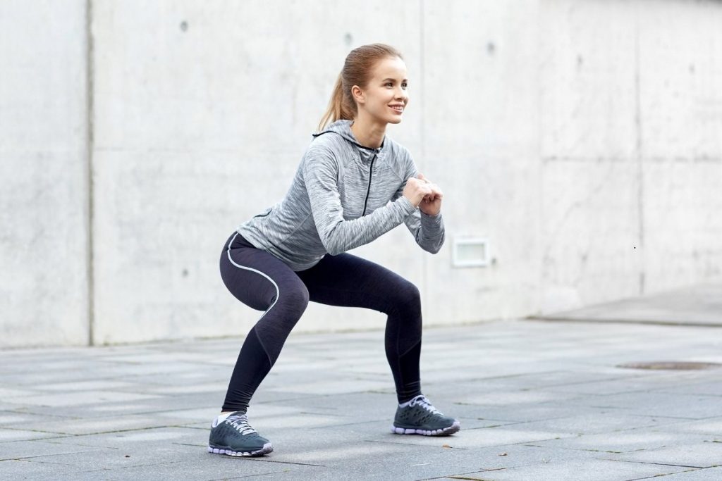 Female performs squats in outdoor setting