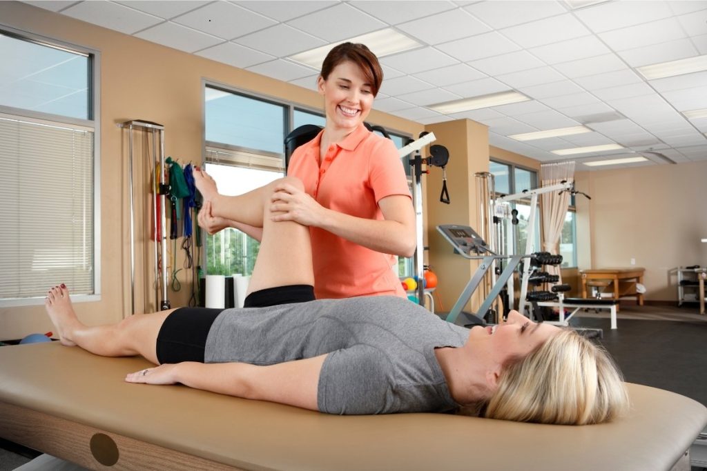 Female physical therapist treating female patients knee