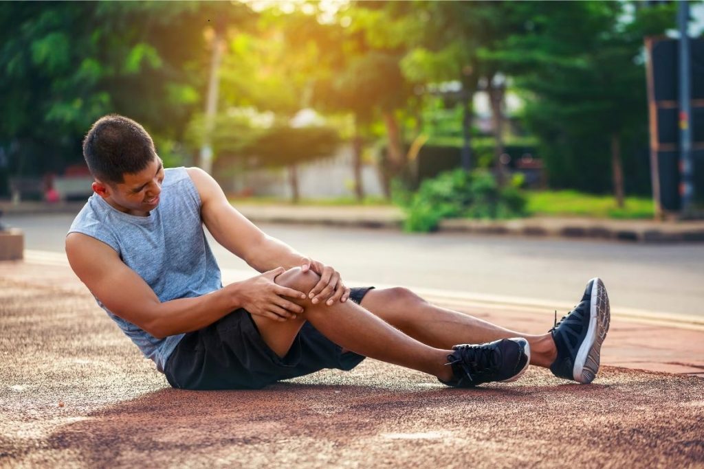 Man holding knee in pain on the floor during workout