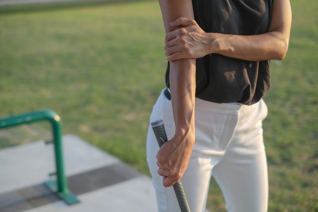 Female golfer holding hurt elbow