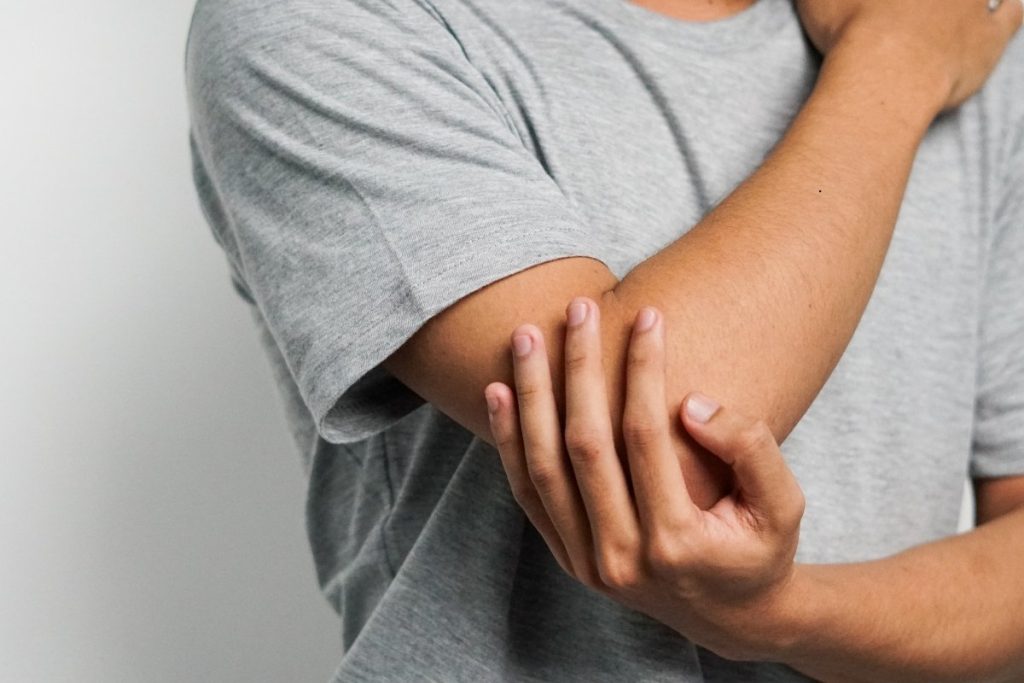 Man holds hurt elbow