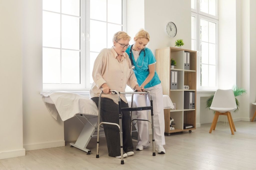 Elderly female patient helped up the stairs by female physical therapist
