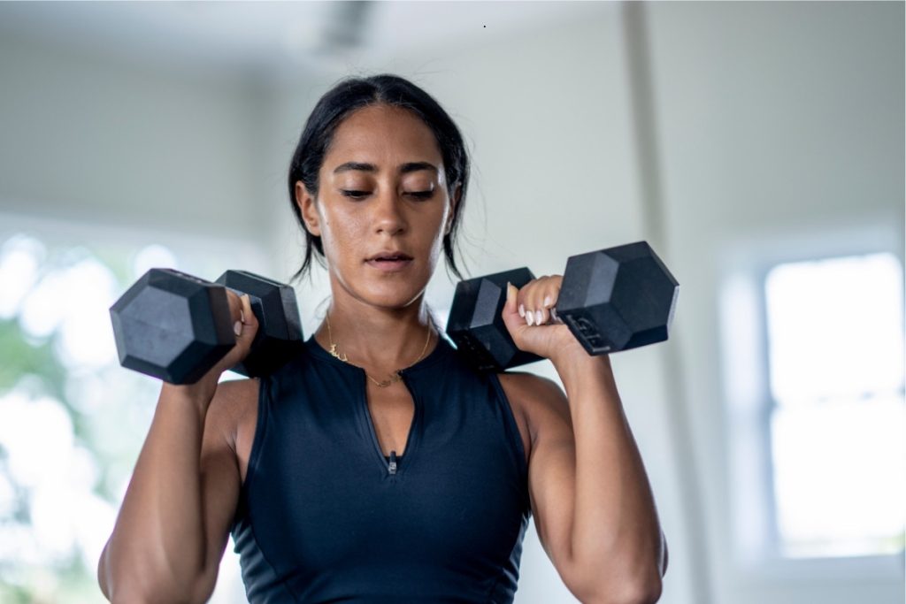 Female preparing to perform shoulder press with dumbbells