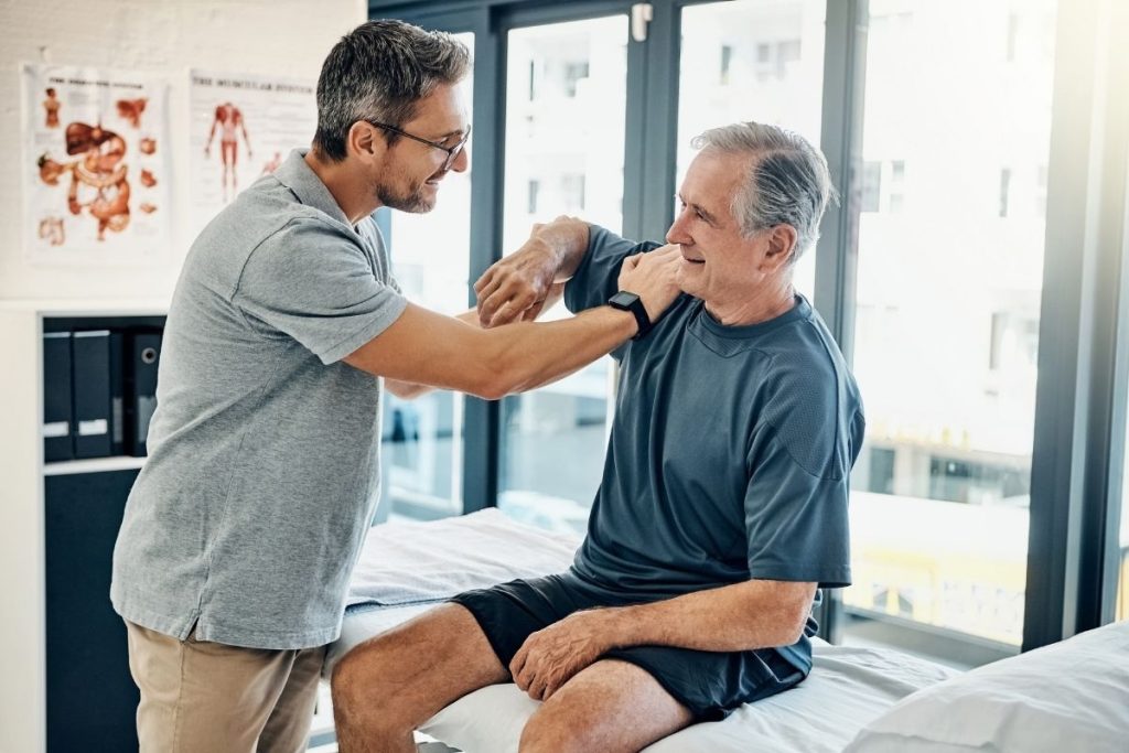 Male physical therapist treating male patient's shoulder