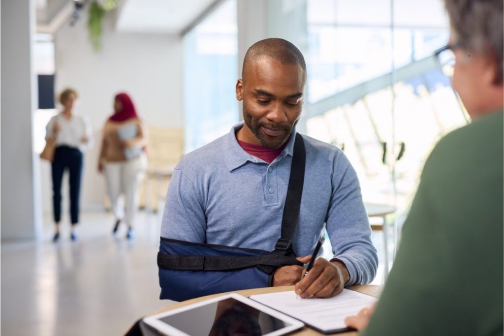 Male with elbow brace signing a paper