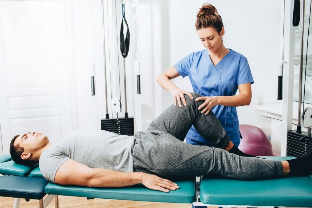 Female physical therapist treating male patient's knee