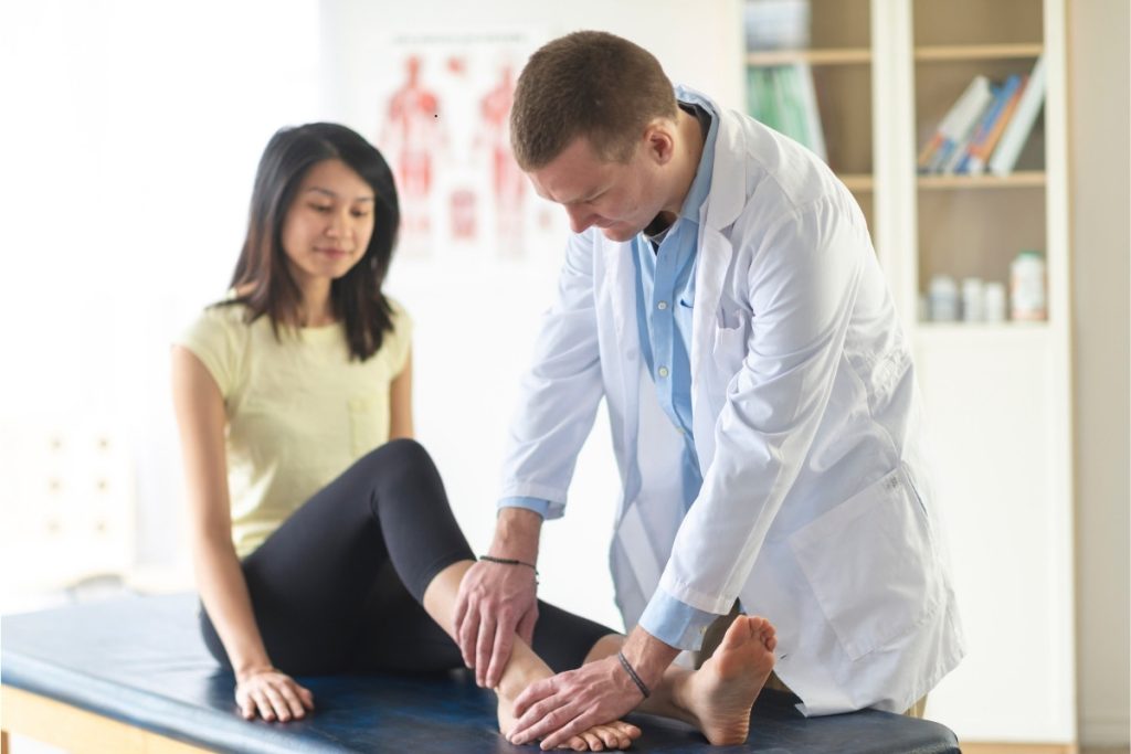 Male physical therapist treating female patient's ankle