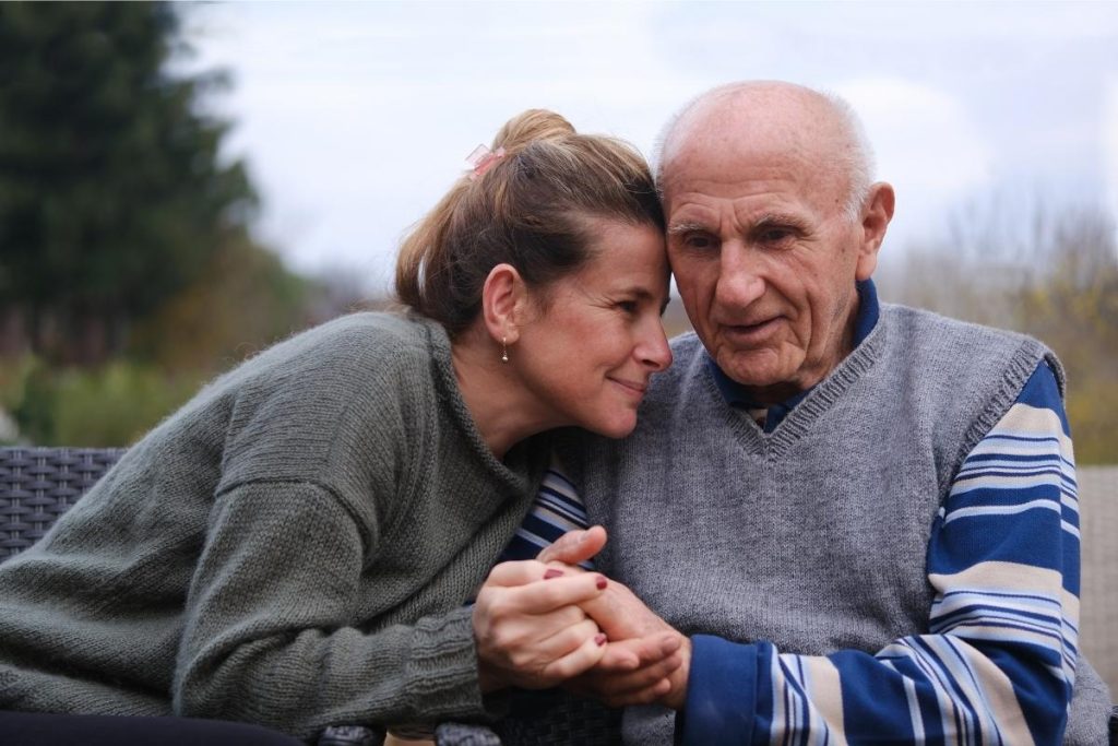 Adult female holds hands with elderly man
