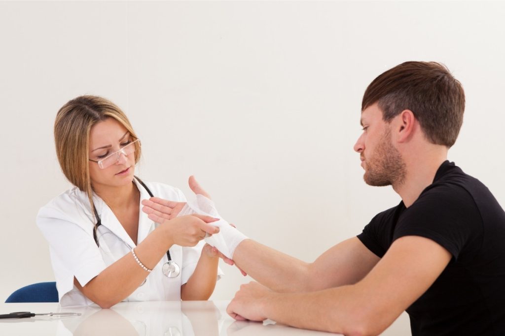 Female doctor tending to male's injured wrist